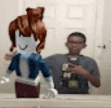 a man is taking a picture of himself in a bathroom mirror while holding a doll .