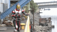 a man in a kamen rider costume is standing next to a railing .