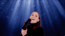 a woman in a black turtleneck is holding a microphone and laughing