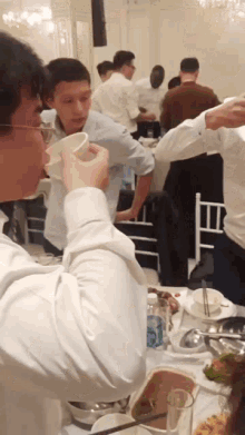 a group of people are sitting at a table with plates of food