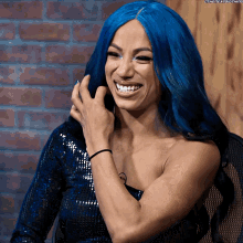 a woman with blue hair is smiling and wearing a blue dress