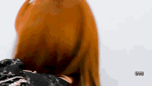 a woman with long red hair is covering her face with a black shirt .