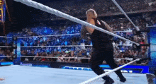 a wrestling match is being held in a stadium with a crowd watching .