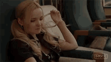 a woman is sitting in a chair with her hand on her hair .