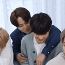 a group of young men are hugging each other while sitting in a room .