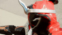 a person in a red and black costume with a sword on their head