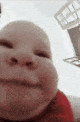a close up of a baby 's face making a funny face while looking at the camera .