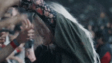 a woman with long white hair is dancing in front of a crowd at a concert .