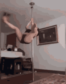a pole dancer is doing a flip on a pole in a room