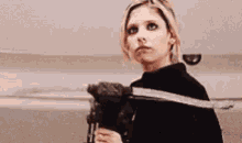 a woman is holding a sword and looking at the camera .
