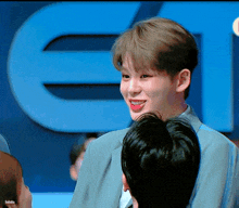 a man in a suit is smiling in front of a large blue letter e.