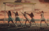 a group of girls are dancing in front of a bus stop at sunset