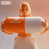 a woman is holding a large orange and white capsule with the word datagram on it