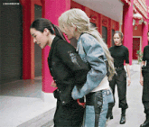 a woman in a denim jacket is holding another woman 's waist