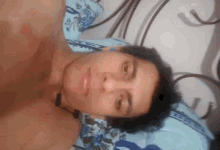 a shirtless man laying on a bed with a blue and white pillow