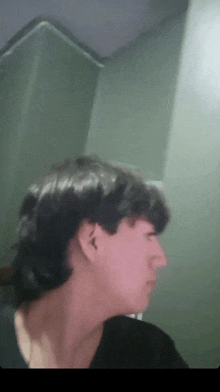 a close up of a man 's face with a green wall in the background