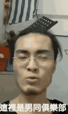 a man wearing glasses and a ponytail has chinese writing on his face