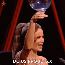 a woman in a ponytail is holding a trophy over her head and says do us proud xx