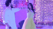 a man and a woman are dancing together in front of a purple background .