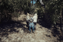 a group of people standing on a dirt path with trees in the background