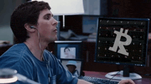 a man wearing headphones is looking at a computer screen with a bitcoin symbol