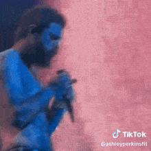a man with blue paint on his face is singing into a microphone