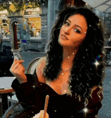 a woman with curly hair is sitting at a table with a straw in her mouth .