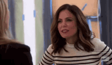 a woman is wearing a striped sweater and talking to another woman .
