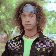 a man with curly hair is wearing a headband and a neon shirt