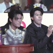 two men are sitting next to each other and one of them is clapping his hands