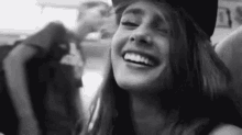 a black and white photo of a woman wearing a hat and smiling on a plane .