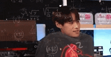 a man is standing in front of a blackboard with math problems on it .