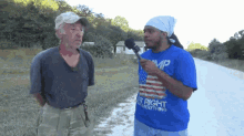 a man wearing a blue shirt that says mp is talking into a microphone