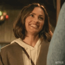 a woman is smiling while standing next to a man and looking at the camera .