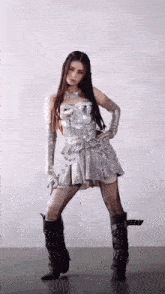 a woman in a silver dress and black boots is dancing on a tiled floor .