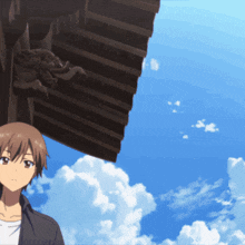 a man stands under a roof with a blue sky behind him