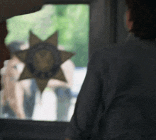 a man stands in front of a window with a police star on it