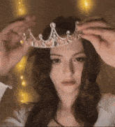 a woman is wearing a tiara on her head and looking at the camera .