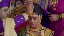 a man is putting a necklace on a woman 's head with a starplus logo on the bottom right