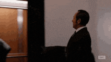 a man in a suit and tie is standing in front of a white board that says abc on it