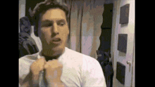 a man wearing a white shirt is standing in a room