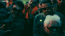 a man with a mustache wearing goggles is in a crowd of people with xtoms / 2006 written in the corner