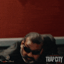 a poster for trap city shows a man in a suit