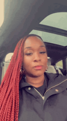 a woman with red braids is sitting in a car .