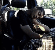 a man in a black shirt is sleeping in a car seat