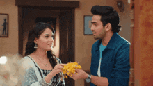 a man and a woman are looking at each other and the woman is holding flowers