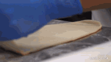 a person is rolling out a piece of dough on a marble surface .