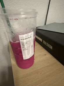 a cup of vt dragon drink sits next to a raiders book