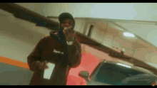 a man wearing a supreme hoodie is singing into a microphone in a garage