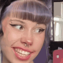 a close up of a woman 's face with a nose ring and piercings .